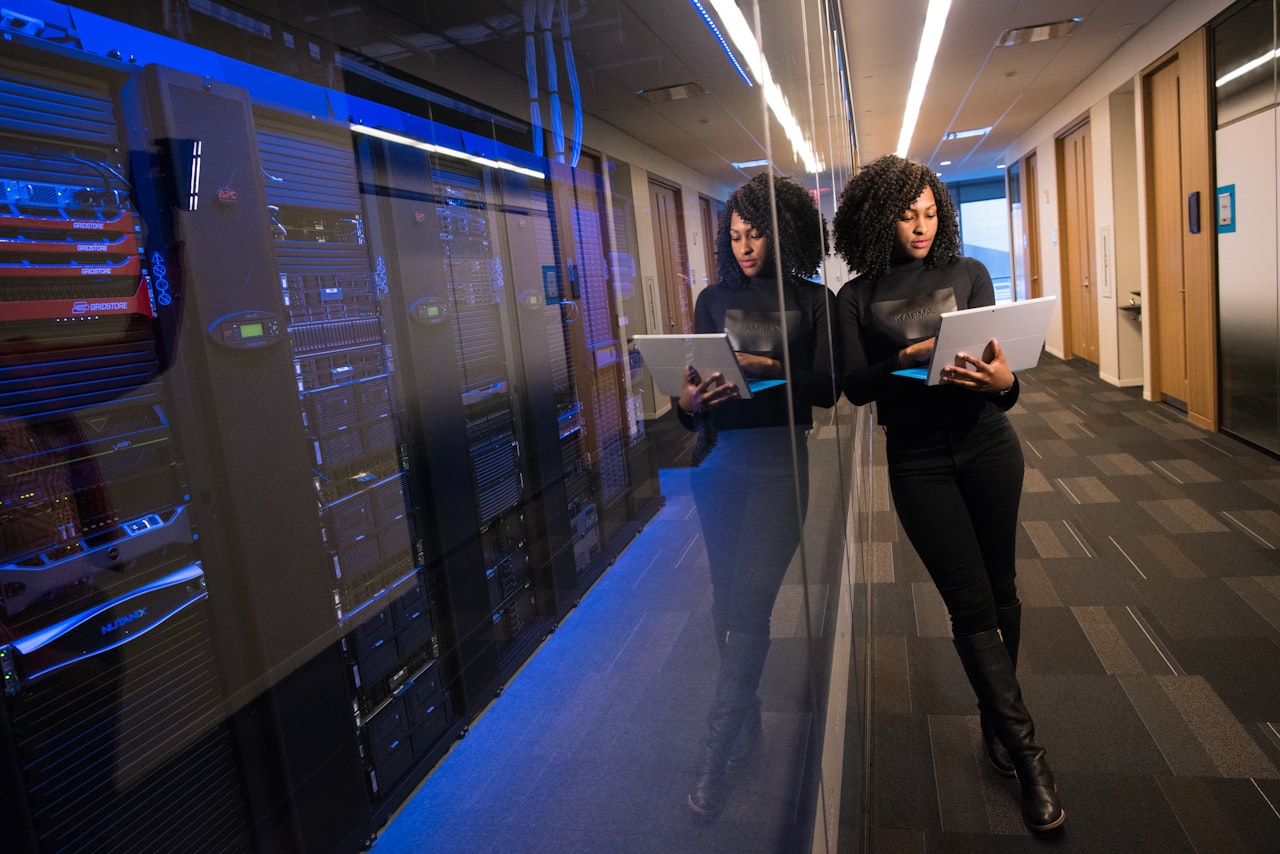 Engineer reviewing systems on a laptop beside secured server racks